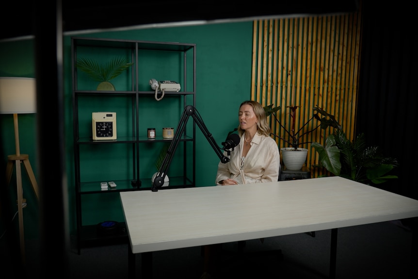 A blonde woman sits in a recording studio with her eyes closed 