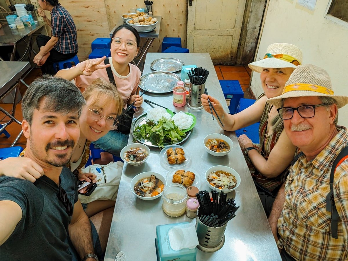 Group of travelers taking a selfie at a local Bun Cha eatery in Hanoi, Vietnam.