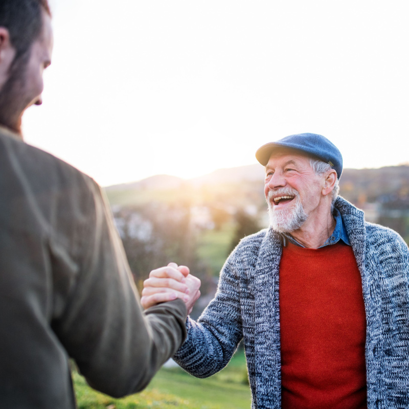 two men shake hands in the countryside