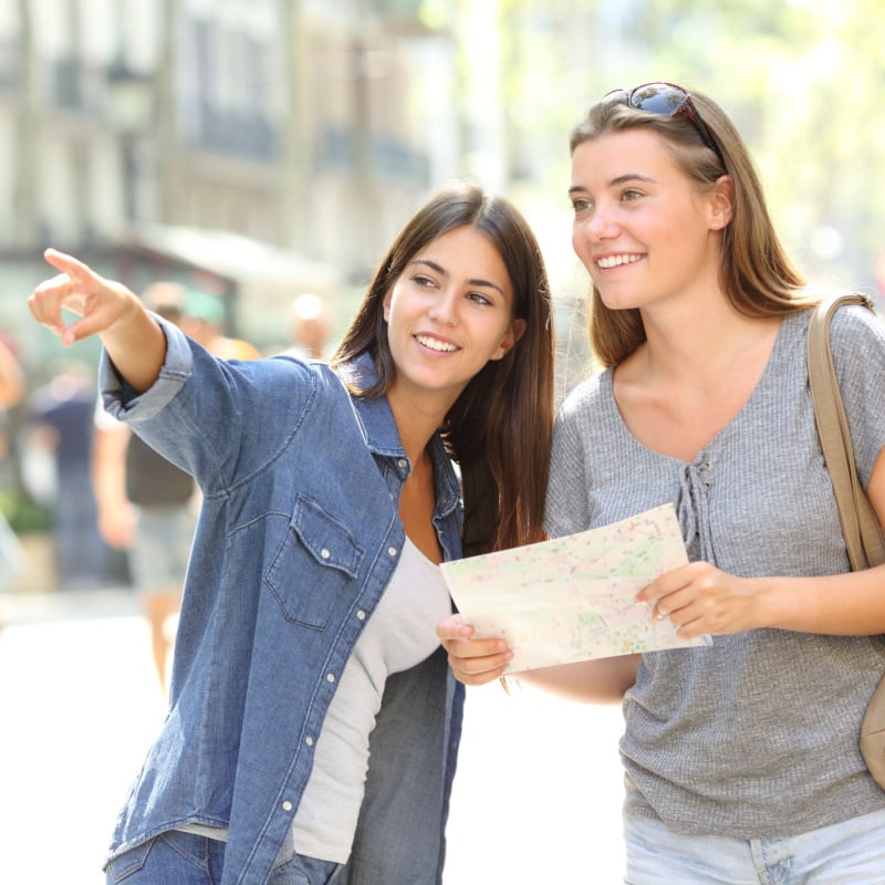 a tourist receives directions from a woman wearing a denim shirt