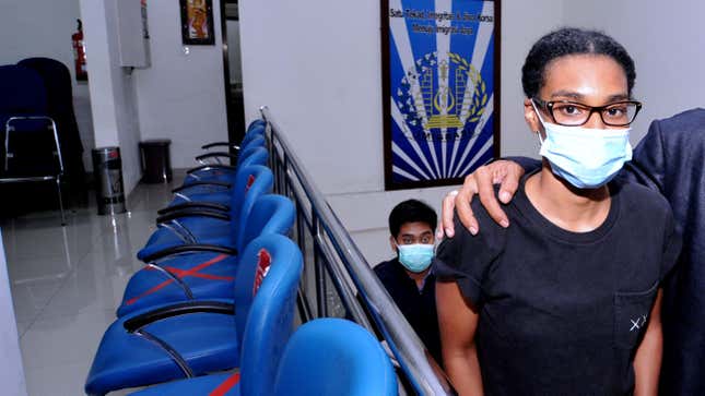 An American woman wearing a Black t-shirt, glasses and a surgical mask looks into the camera after being examined at the Indonesian Immigration office in Denpasar, Bali, Indonesia.