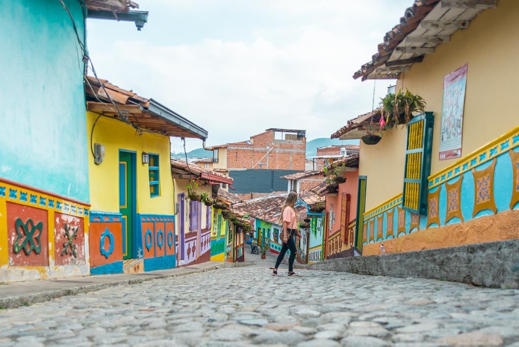 A lady poses for a photo on a colorful street in Guatape, Colombia