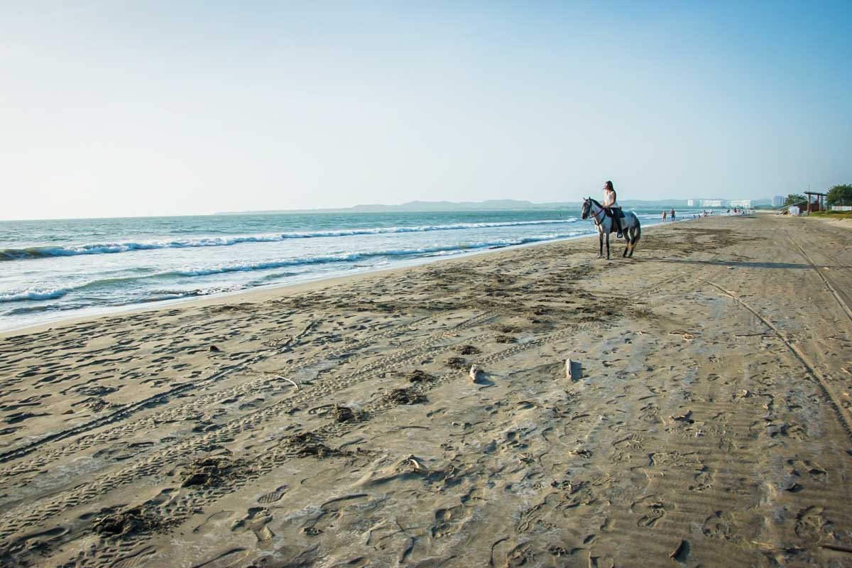 A person rides a horse on a beach in Cartagena, Colombia