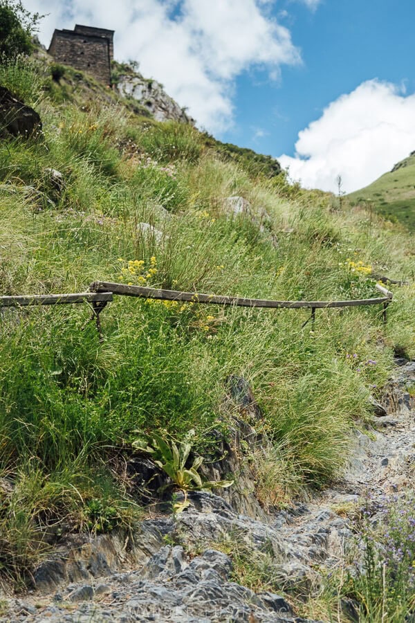 A steep walking path with wooden rails leads to Mutso Castle in Khevsureti.