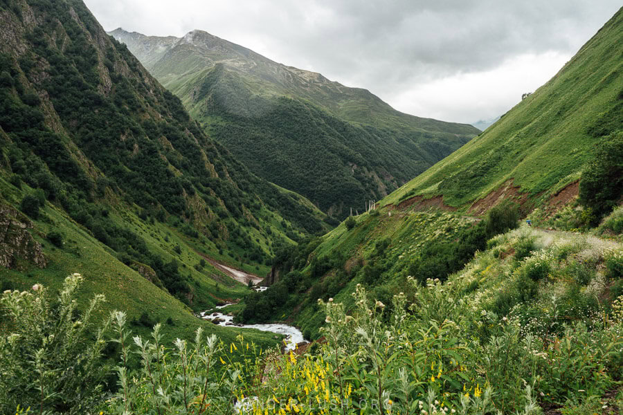 A river travels through high green mountains in Juta, Georgia.