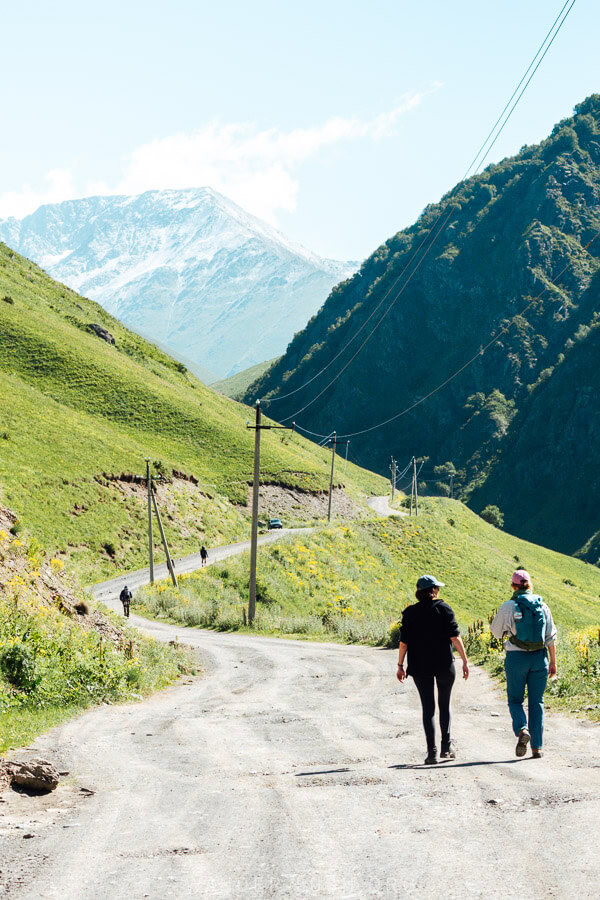 Tourists walk on a dirt road in Juta, Georgia.