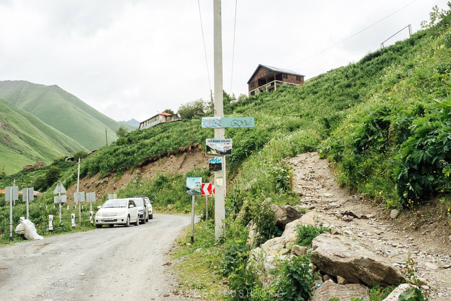 A hiking trail in Juta starts from the road, with a sign marking the way to the Fifth Season cabin.