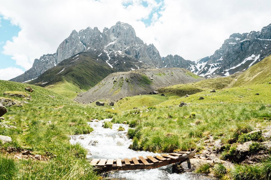 A wooden bridge crosses a river in the Juta Valley.