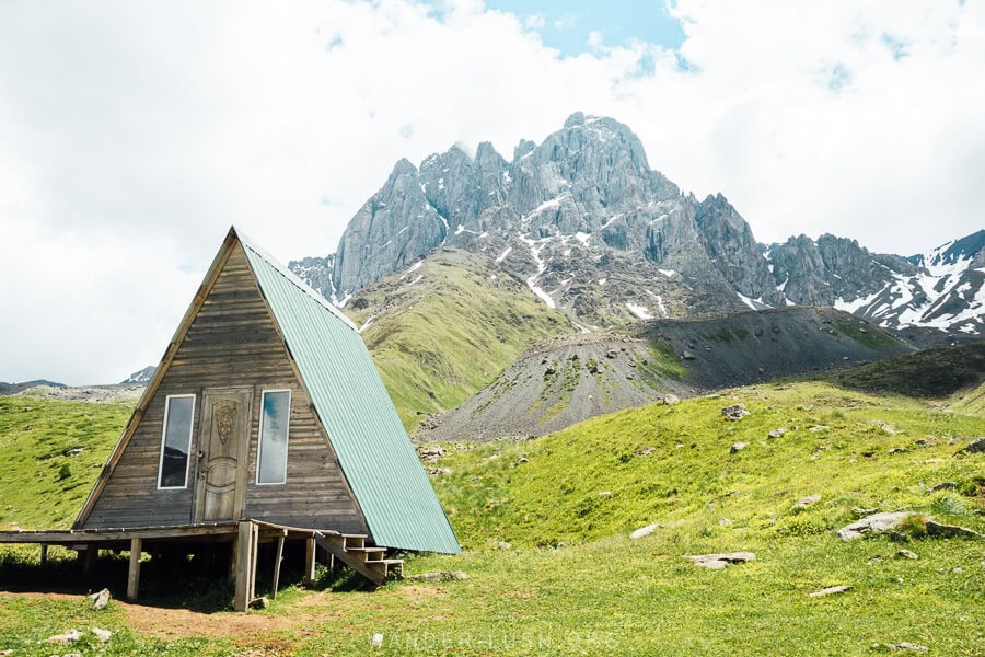 A green A-frame cabin in front of the mountains in Juta, Georgia.