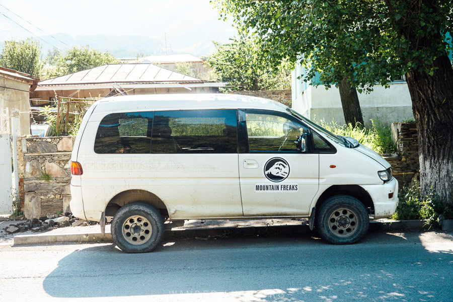 A white Delica van parked on a street in Kazbegi, Georgia.