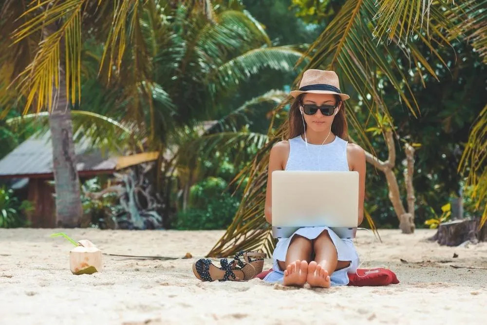 Woman working on laptop on the beach — Shutterstock