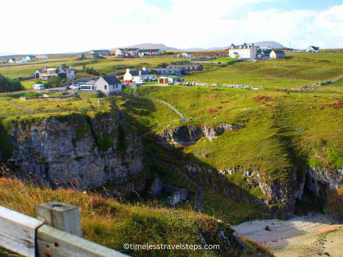 view of the Clifftop car park with the surrounding landscape, and buildings including steep steps leading down to the Smoo Cave site on a bright and sunny autumn day.
