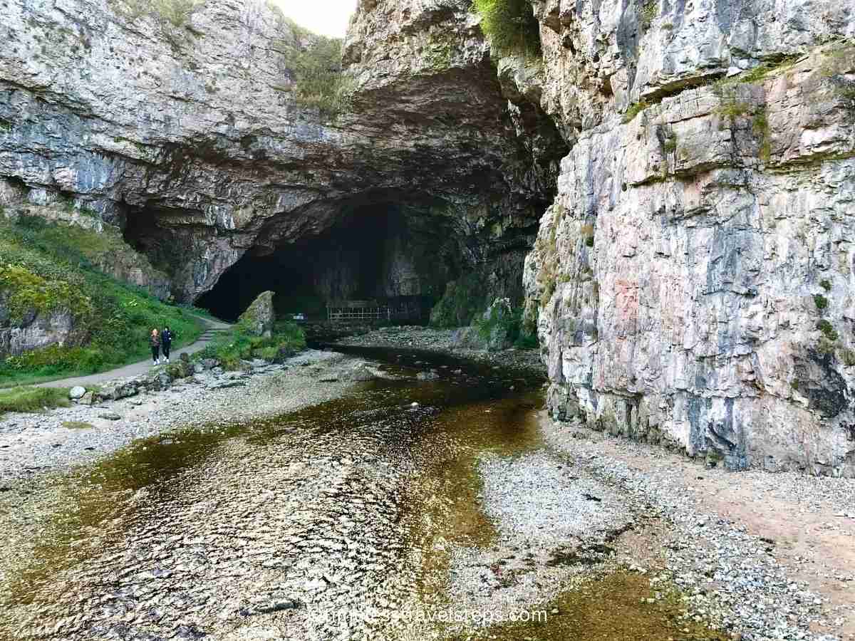 The first sight of the huge entrance to Smoo Cave is both inviting and mysterious. It reveals an impressive, towering archway over 200 feet wide and 130 feet high, framed by rugged cliffs and lush greenery, drawing visitors into its vast, shadowy interior.