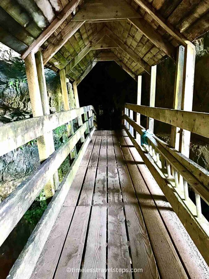 the tunnel like footbridge leading to the first chamber for a view of Smoo Cave Waterfall