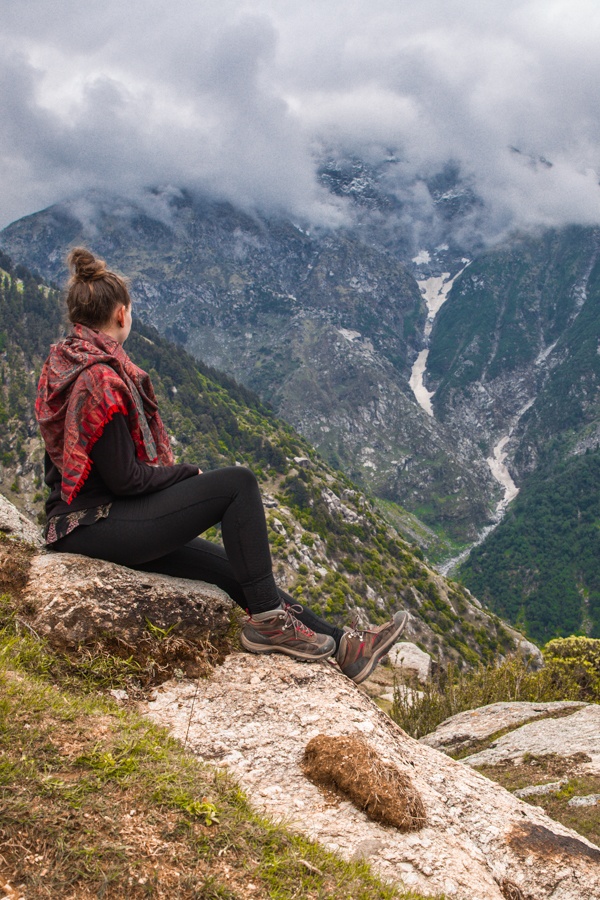 Solo woman taking a break while hiking with a mountain landscape in the background.