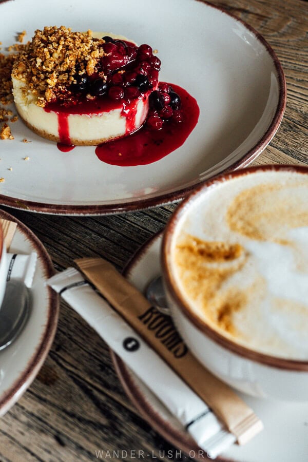 A cheesecake with berries and a cup of coffee on a table at Rooms Kazbegi restaurant in Georgia.