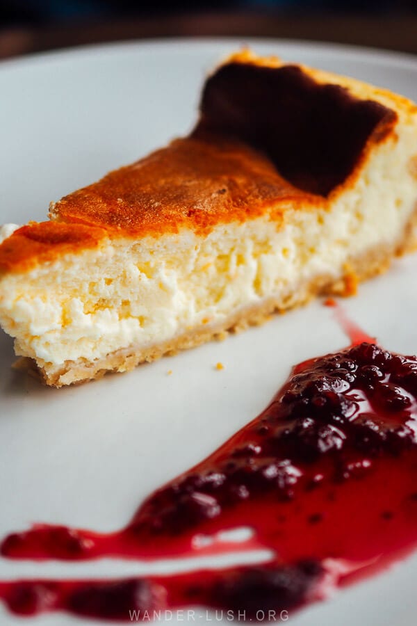 A slice of cheesecake on a white plate with berry compote.