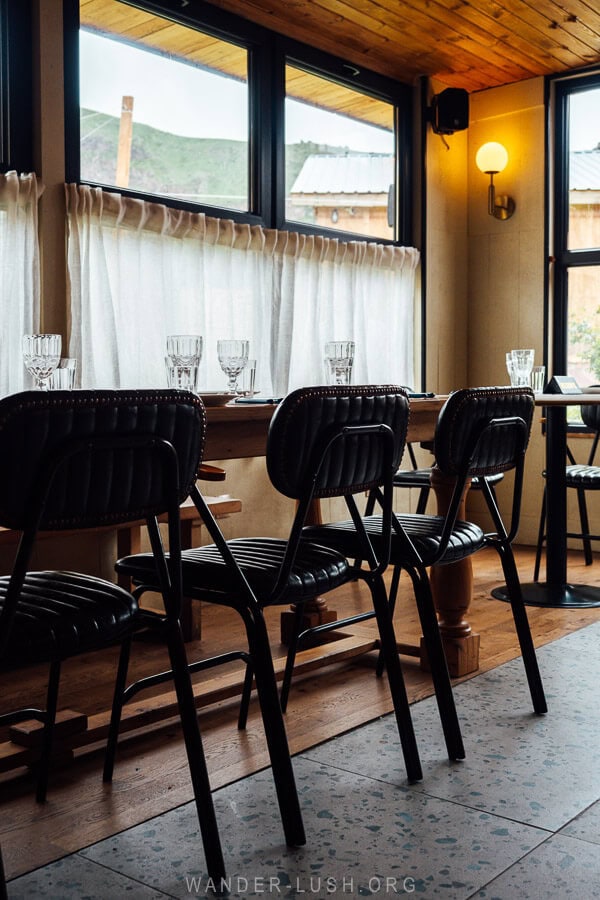 A dimly lit restaurant with beautiful seats and windows overlooking the Caucasus mountains.