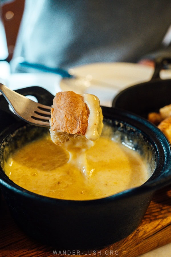 A man dips a bread crouton into cheese fondue at a restaurant in Georgia.