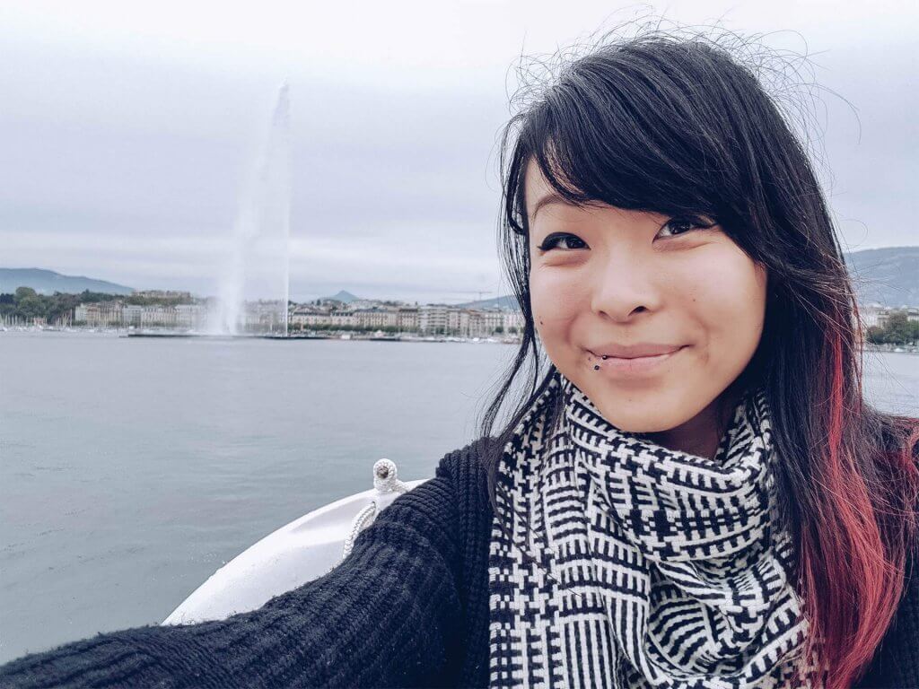 Woman taking a selfie in front of a fountain in Geneva Switzerland.