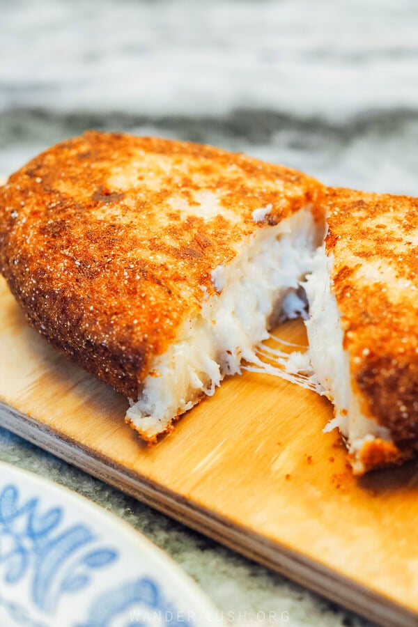 A piece of Chvishtari cheesy cornbread on a wooden board at an Old Tbilisi restaurant.