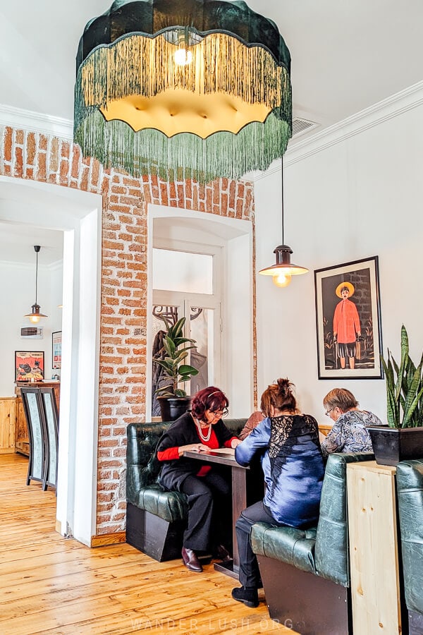 A light filled dining room with a big chandelier and a table of women enjoying a meal at Vakhtanguri's Chebureki in Tbilisi, Georgia.