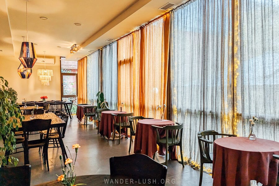 Amo Rame Bani, a beautiful restaurant in Tbilisi with full-length windows and linen curtains.