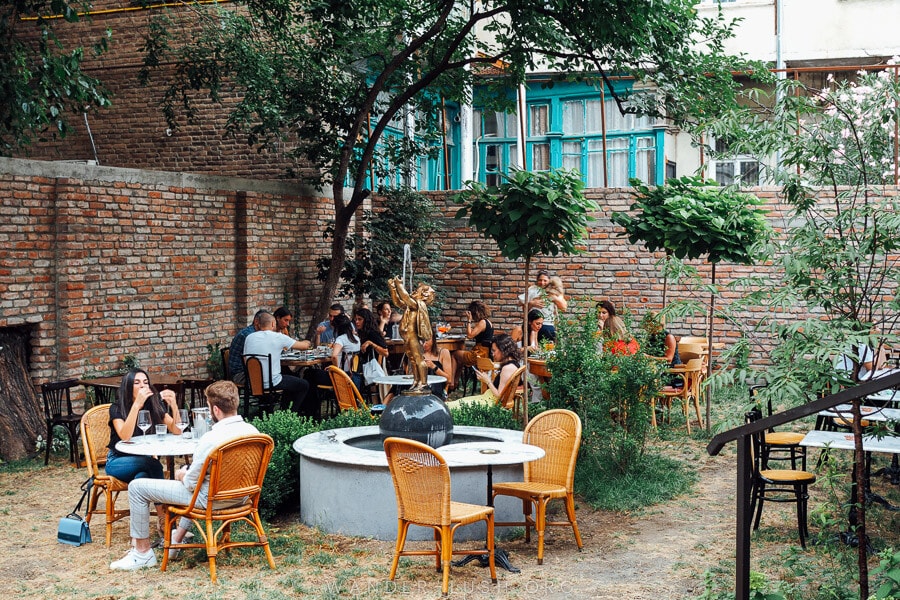 Tables arranged around a decorative fountain at Ninia's Garden cafe in Marjanishvili.