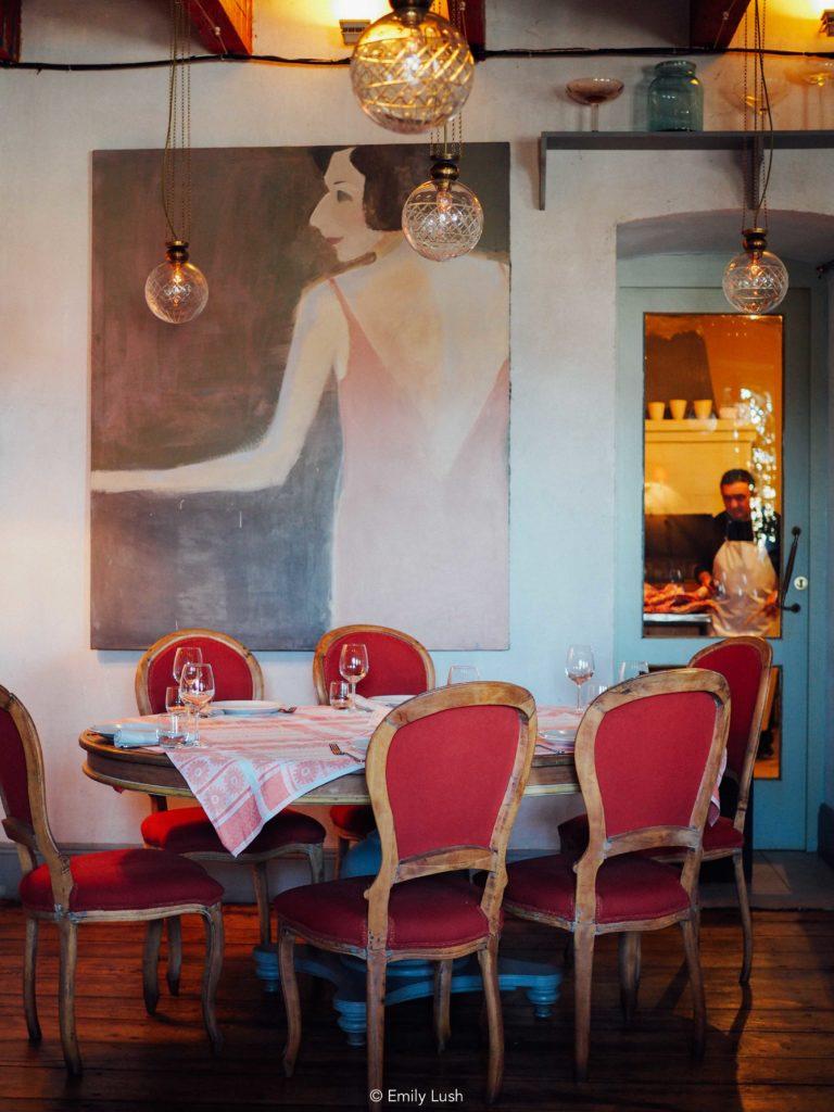 A beautiful dining room with a painting of a woman on the wall.