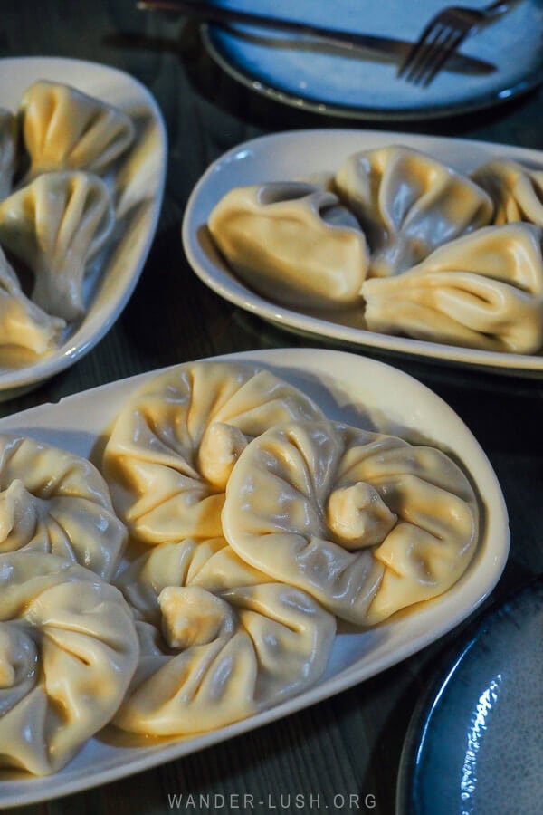 Three plates of khinkali dumplings on a restaurant table in Tbilisi.