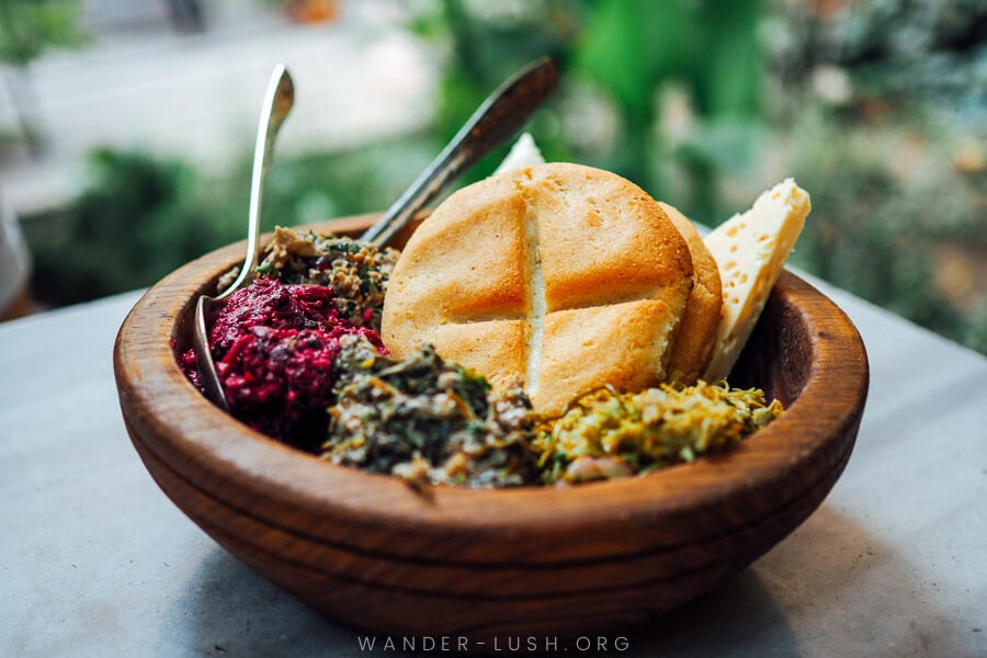 A wooden bowl filled with colourful Pkhali and cornbread - Ghobi at Shavi Lomi restaurant.