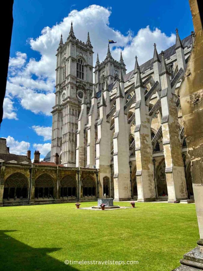 view of the quadrangle from the cloisters. The vibrant green grass and part of the cloisters and building of the Abbey from the other side can be seen. 