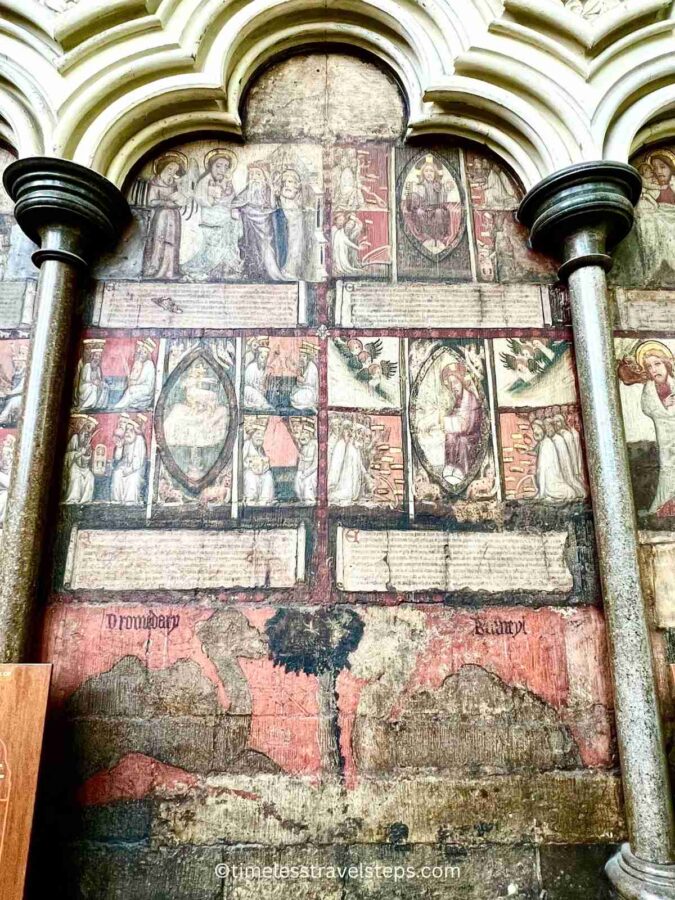 Image of the murals in the Chapter House at Westminster Abbey. The artwork, though some sections are faded, still displays rich colours and intricate details. These 14th-century murals depict scenes from the Apocalypse and the Last Judgement, showcasing the historical and artistic significance of the space.