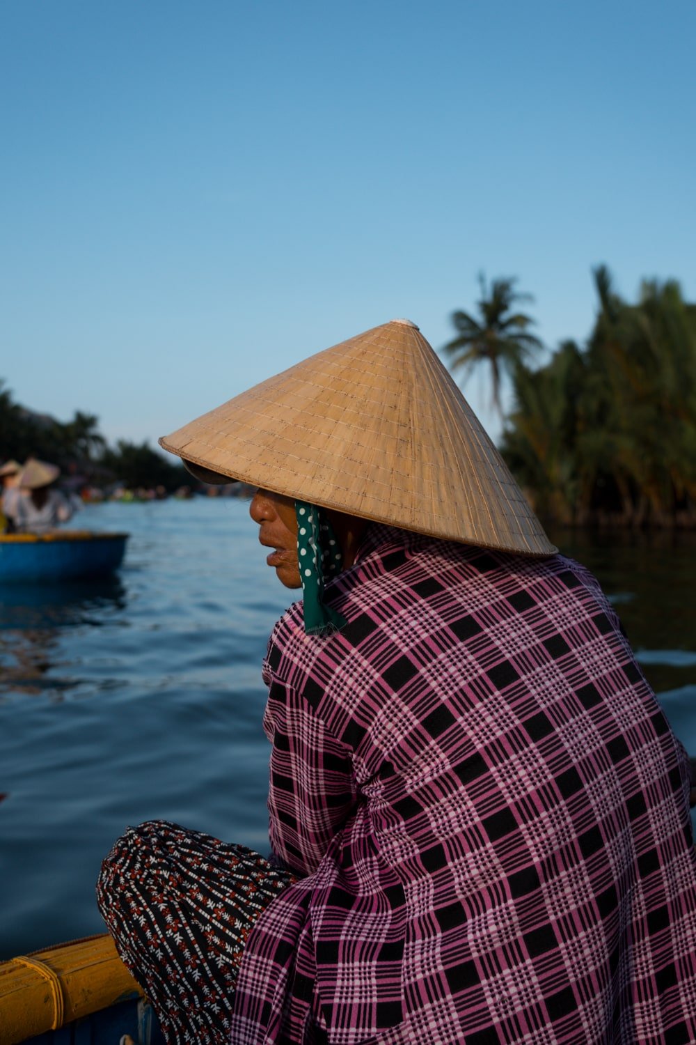 Vietnamese woman wearing a conicle hat and rowing a basket boat near Hoi An, Vietnam.