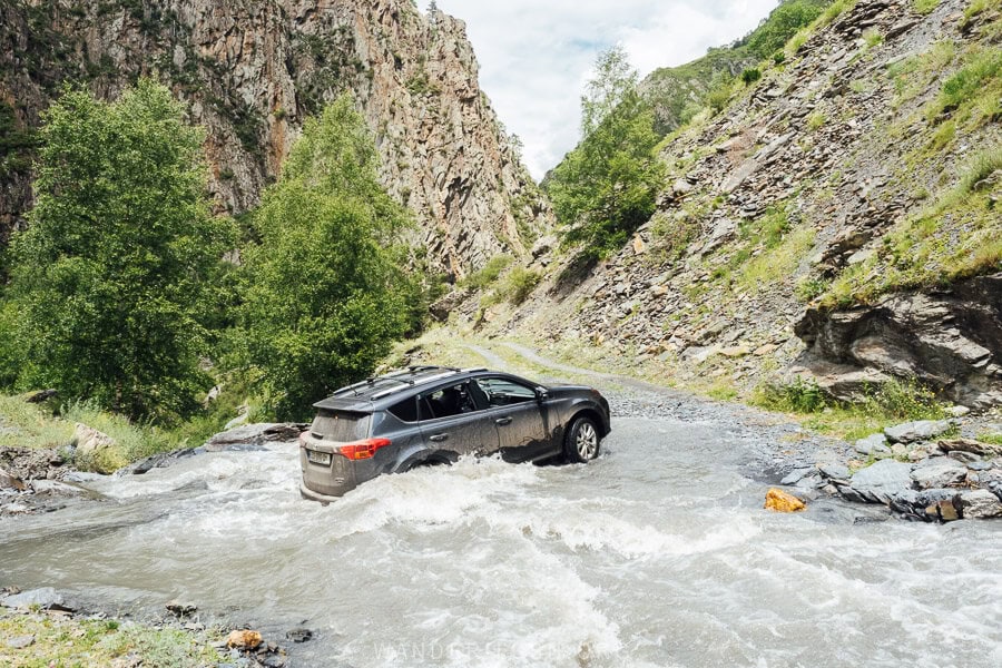 A car crosses a river in Khevsureti on the road to Khonischala.