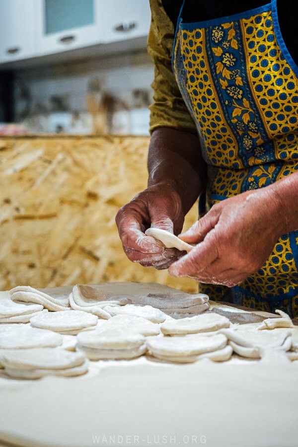 A woman in a yellow apron makes khinkali dumplings.