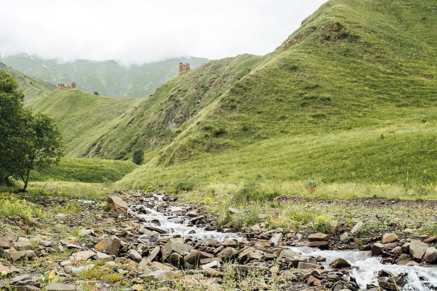 Kistani Fortress, an abandoned village and watchtower in a valley in Khevsureti with a river coursing past.