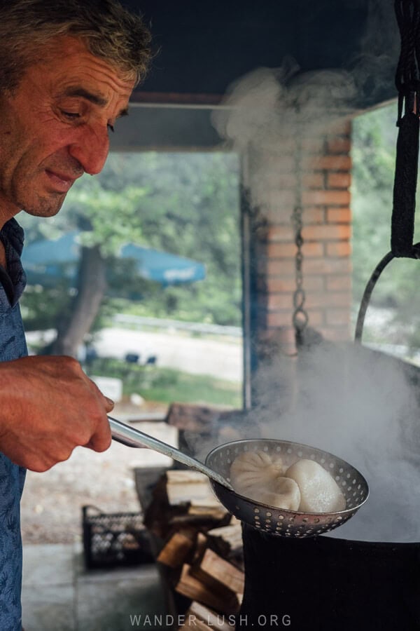 A man fishes fresh khinkali dumplings out of a pot of boiling water at an open-air restaurant in Khevsureti.