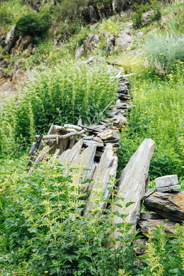 A stone fence surrounded by green grass in a village in Georgia.