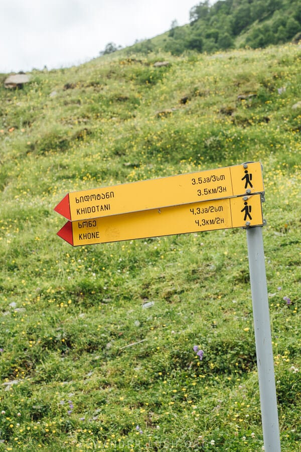 A yellow sign points the way towards two hiking trails in Khevsureti.