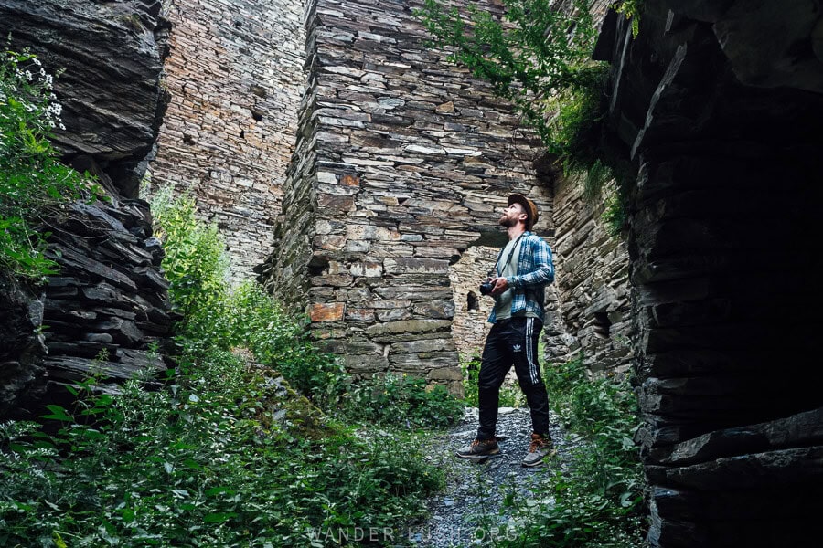 A man exploring the dark and narrow streets of Shatili, an ancient village in Georgia's Caucasus mountains.