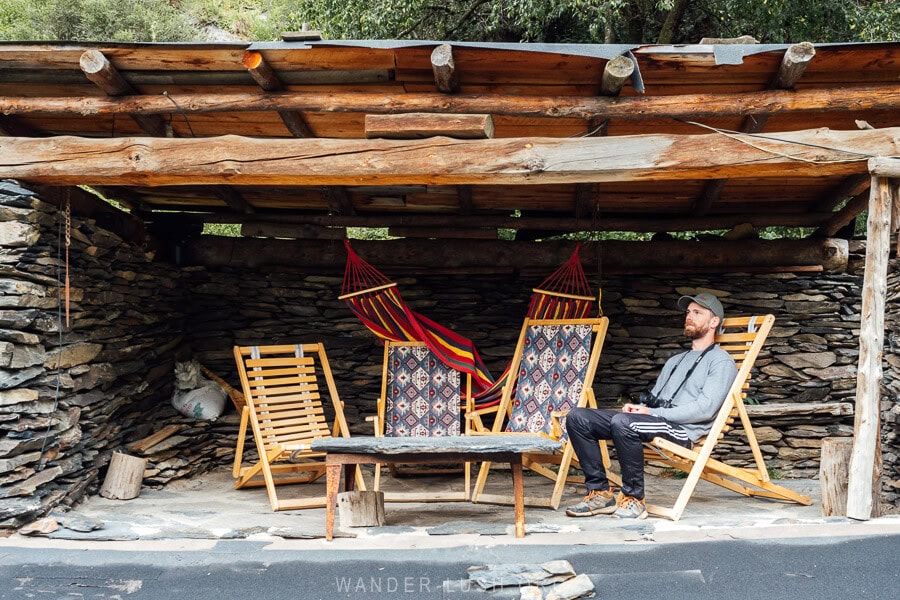 A man sitting on a wooden deck chair on the rooftop terrace of a tower house in Shatili, Georgia.