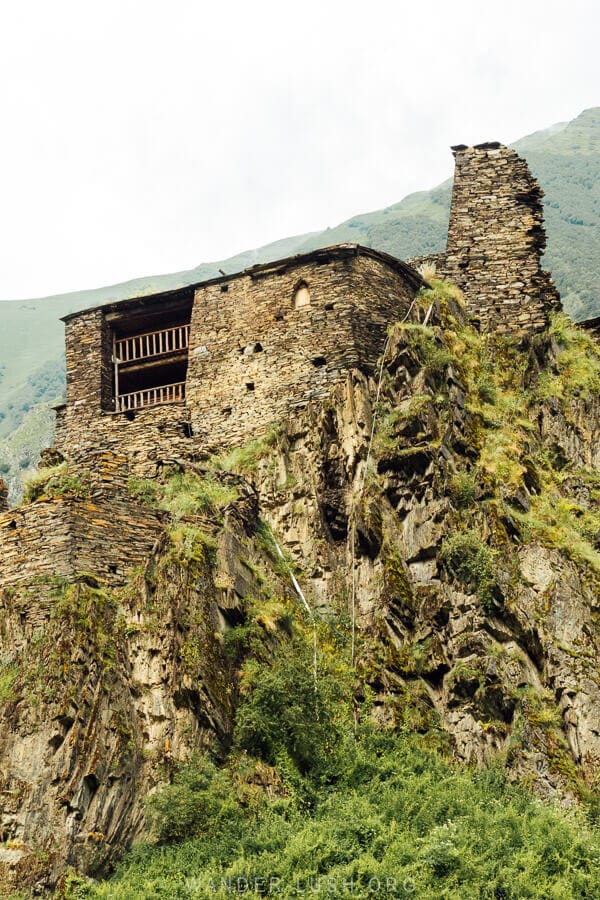 View of Shatili from below, with a tower house emerging from a rocky precipice.