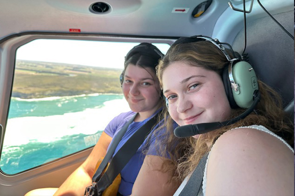 two women in a helicopter flying over the 12 apostles