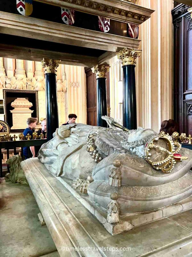 The elaborate tomb of Elizabeth I in Westminster Abbey, adorned with intricate carvings and her effigy lying atop holding a scepter, which bears symbols associated with her mother, Anne Boleyn, and an orb adorned with the Tudor rose, representing her father's House of Tudor. The tomb is located in the Henry VII Lady Chapel and commemorates the reign of the famed monarch.
