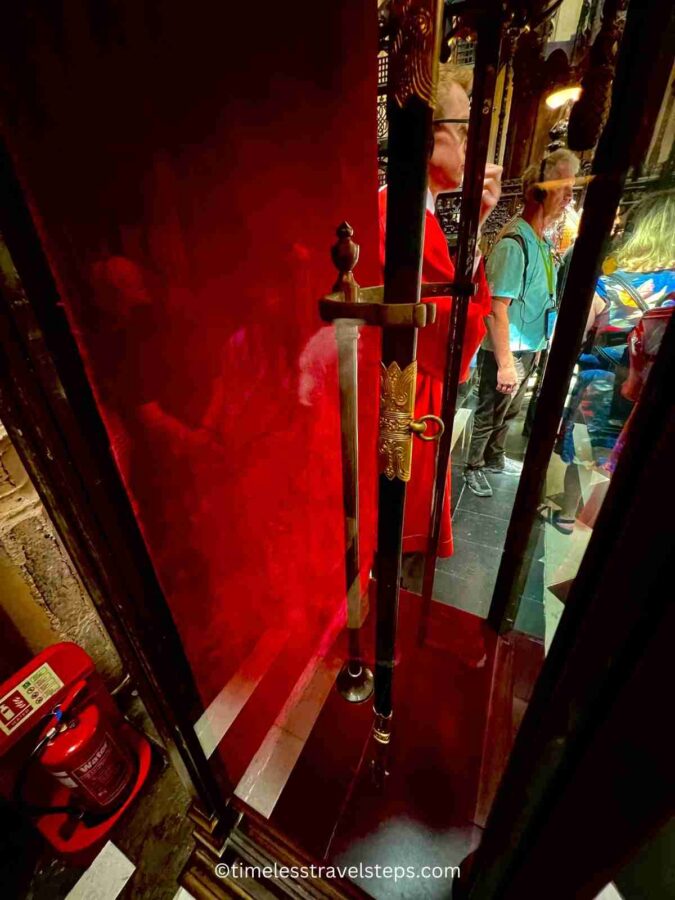 King George's sword encased in a protective glass casing at the Lady Chapel in Westminster Abbey. The sword is displayed prominently, symbolizing royal authority and heritage, with intricate details visible through the glass enclosure
