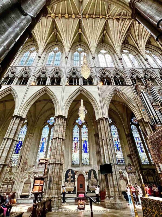 Image of the side wall at Westminster Abbey, featuring elegant arches and vaulted ceiling pillars. The Gothic architecture is highlighted by the intricate stonework and the soaring design of the pillars, creating a sense of height and grandeur
