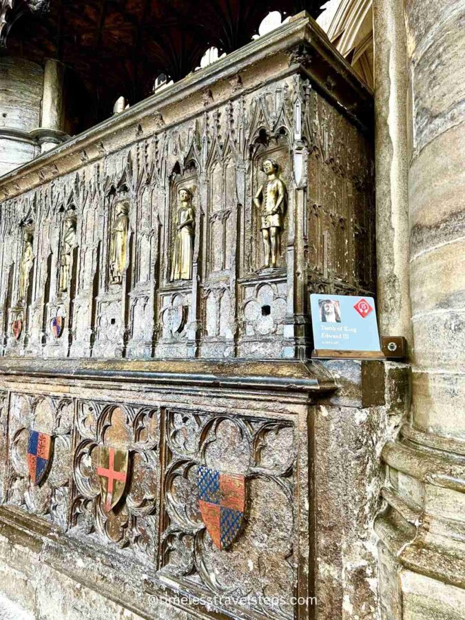 The tomb of Edward III in Westminster Abbey features an intricately carved effigy of the king lying in repose, adorned with detailed medieval armour. Originally surrounded by bronze statuettes (weepers) of his twelve children, only six remain on the south side, including Edward the 'Black Prince', Edmund of Langley, William of Hatfield, Lionel Duke of Clarence, Mary of Brittany, and Joan. Some figurines have enamelled coats of arms below, reflecting the historical significance of his reign and lineage.
