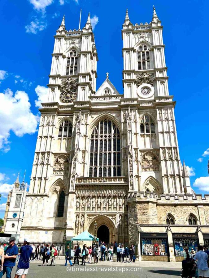 A full view of the west side of Westminster Abbey; the Great West Door, the statues of 20th-century Christian martyrs above the door, the soaring Gothic Revival West Towers, and the clock above the North Transept.