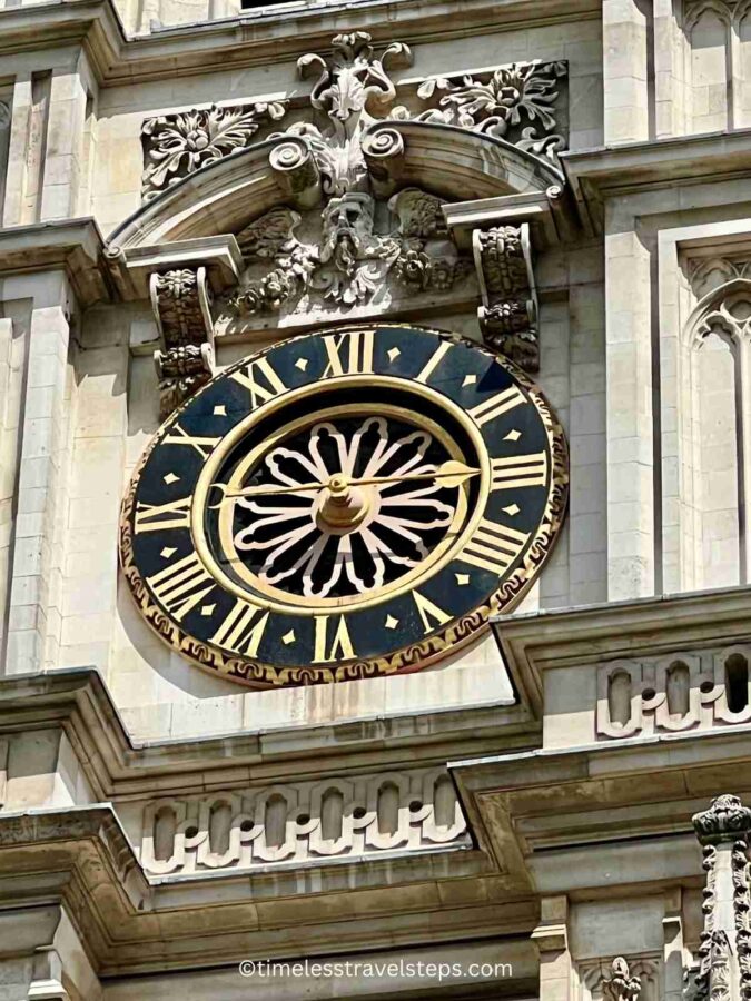 A close-up view of the clock above the North Transept of Westminster Abbey, featuring a large single hand to mark the hours, set within an ornate, Gothic-style frame
